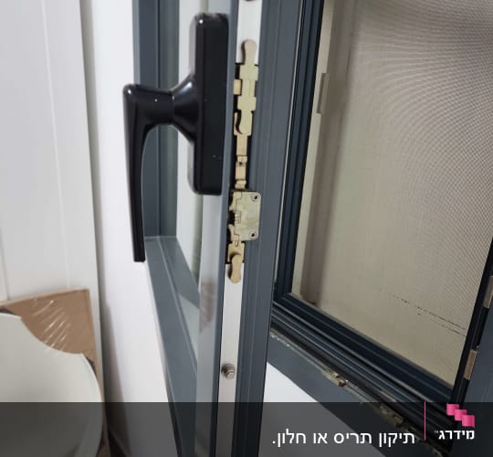חלון פתוח עם ידית שחורה ומנגנון נעילה